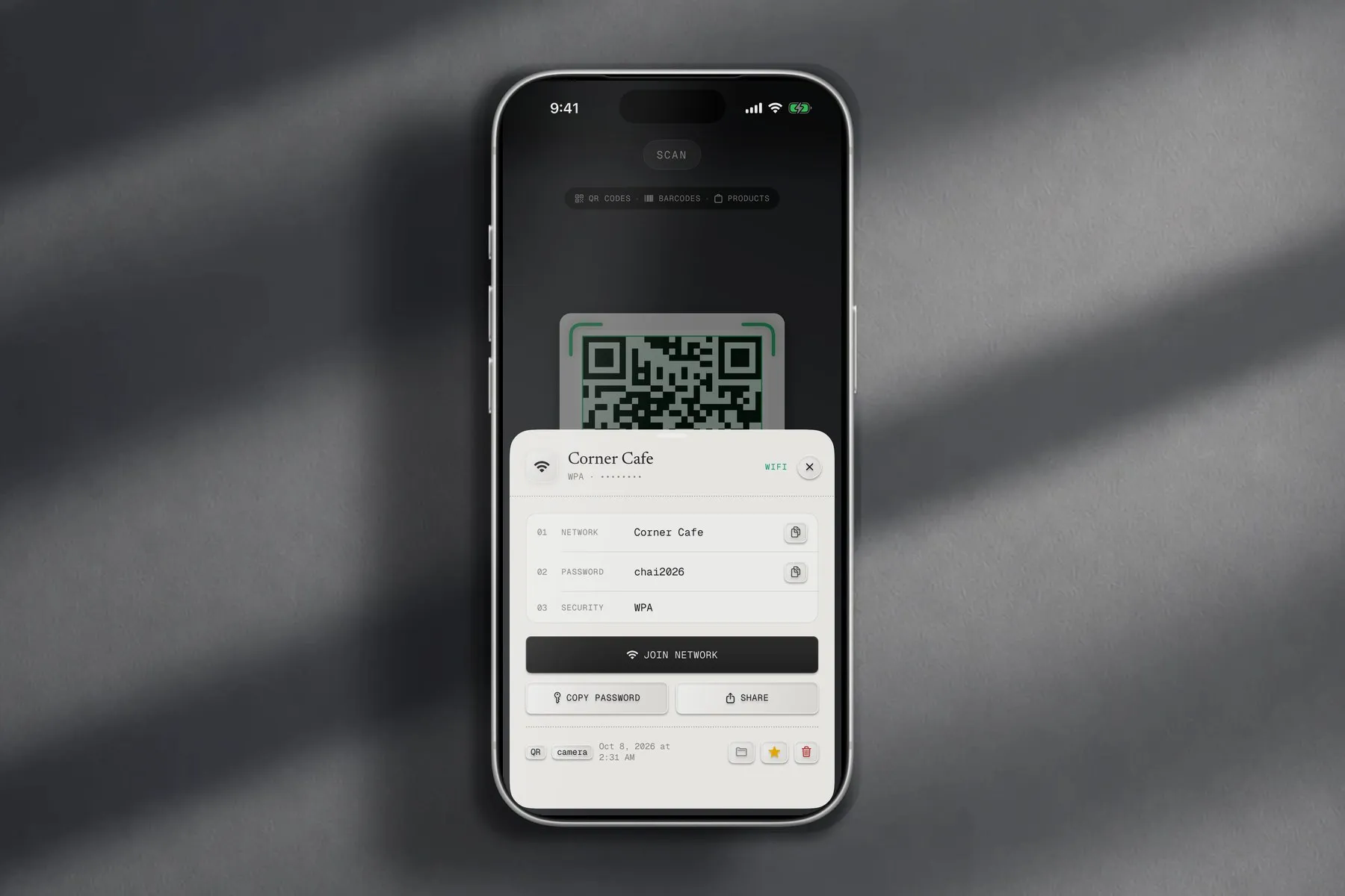 iPhone on a grey wall in window light, showing QR Code Scan Kit after scanning a Wi-Fi QR code: network Corner Cafe, password and a Join network button